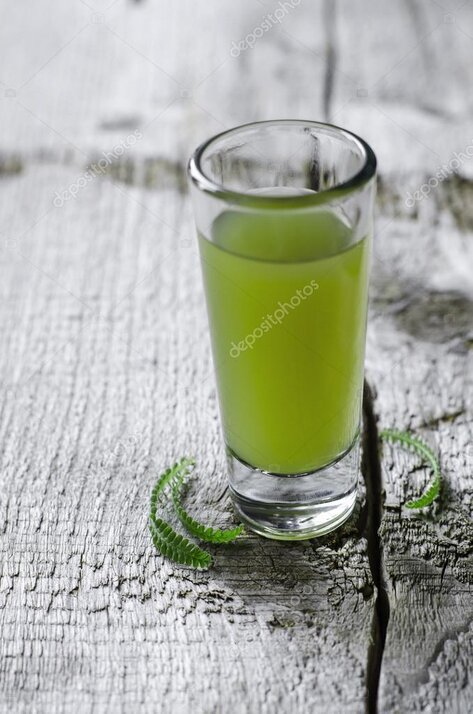 Herbes amères et verre de préparation digestive sur une table en bois