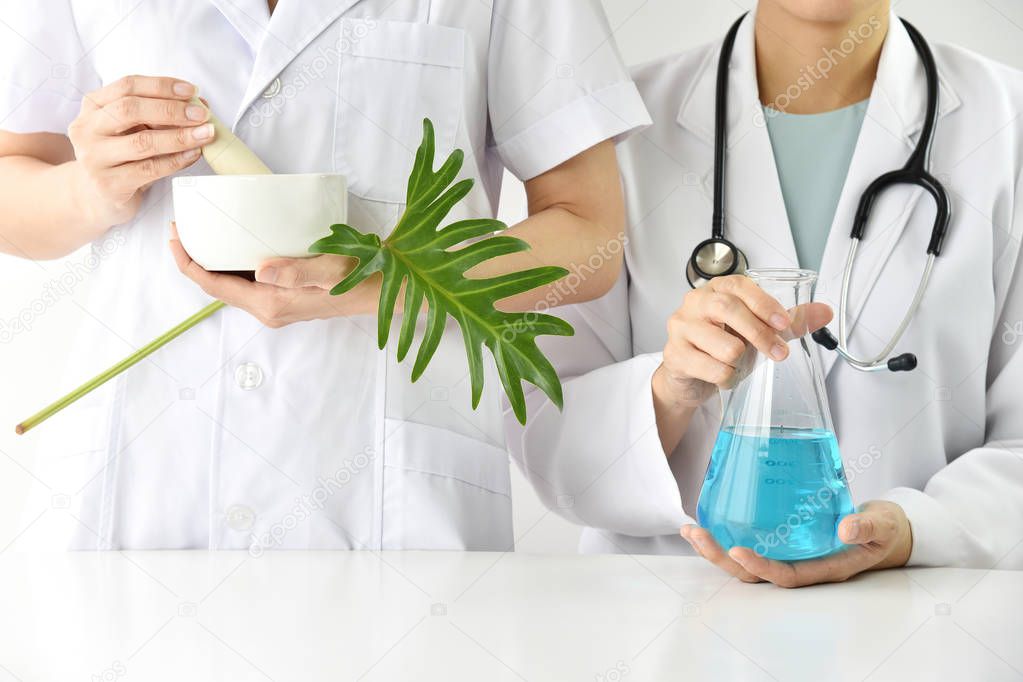 Pharmacien préparant des mélanges de plantes médicinales sur un plan de travail