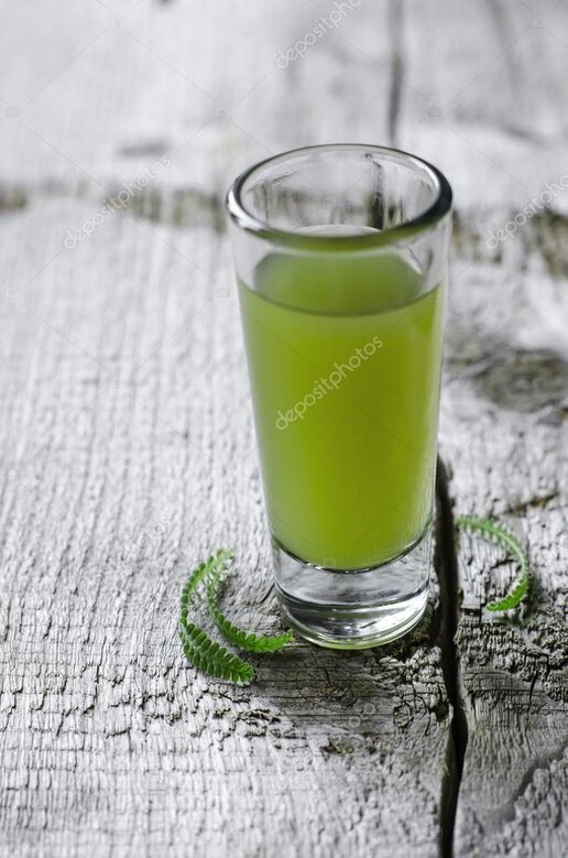 Herbes amères et verre de préparation digestive sur une table en bois